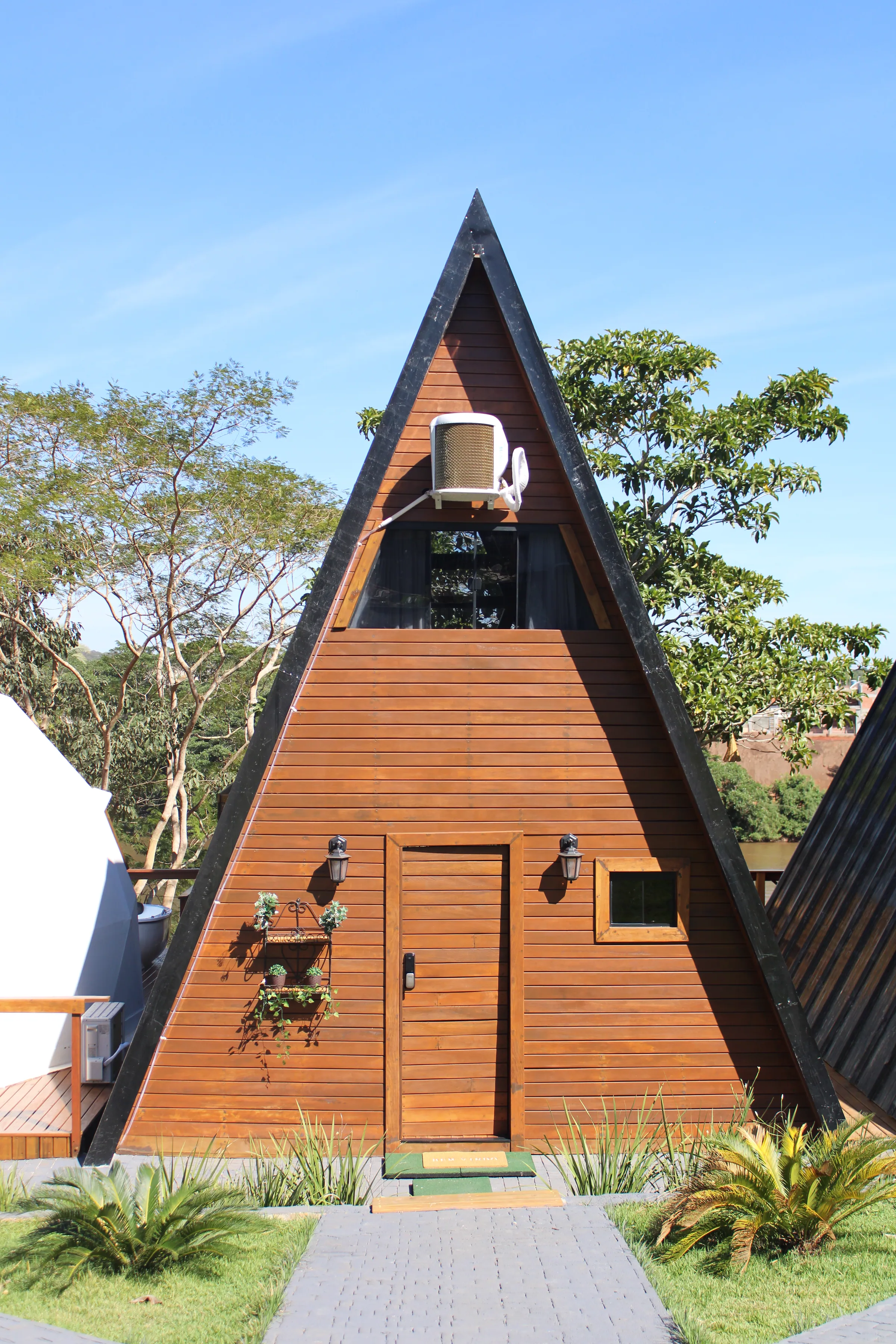 Fachada do chalé A-frame em madeira sob o céu azul